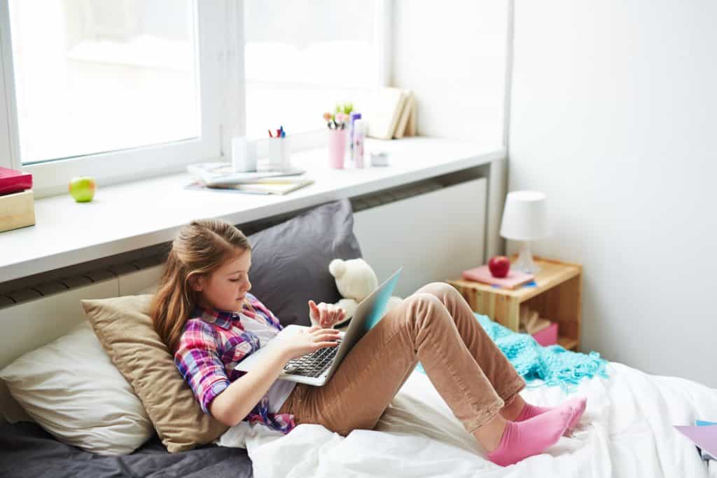 Milyen bútorokat szerezzünk be feltétlenül a gyerekszobába? Teenager Girl on Bed with Laptop