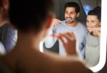 Cheerful couple brushing teeth in bathroom