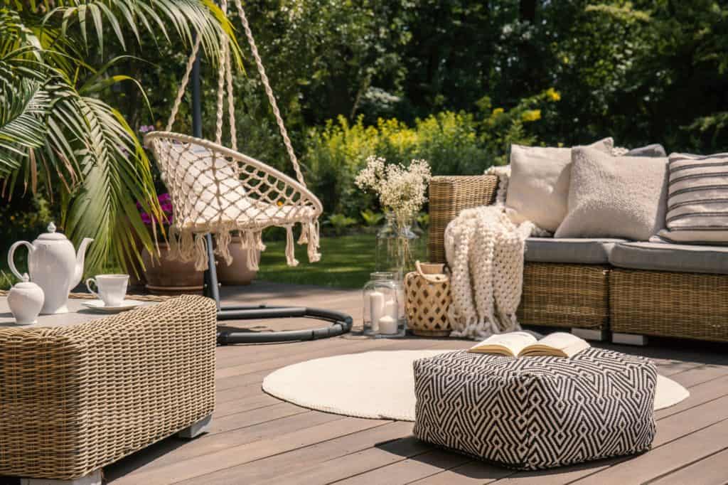 Pouf on wooden terrace with rattan sofa and table in the garden