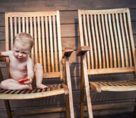 Így varázsolj az erkélyedből különleges birodalmat Small girl sitting on wooden chair on a patio in summer, eating watermelon.